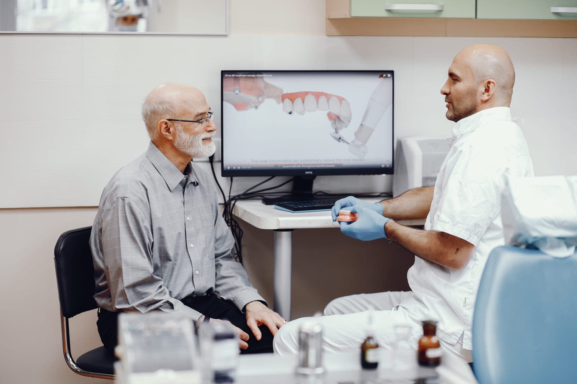 Older patient in the dentist chair discussing dentures