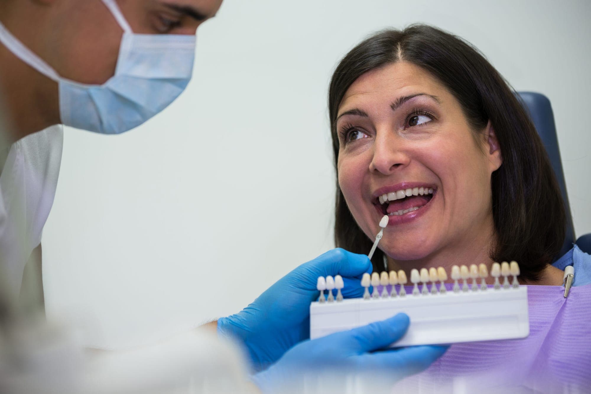 Dentist matching a veneer shade to a smiling patient